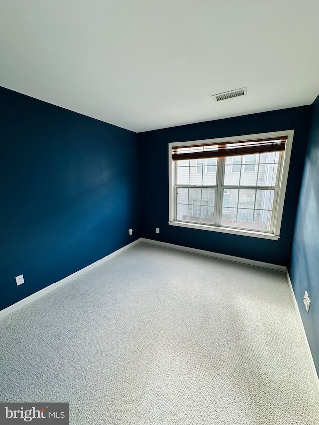 carpeted empty room featuring a healthy amount of sunlight, visible vents, and baseboards