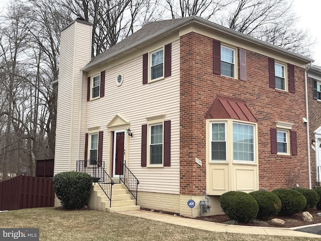 view of front facade featuring a chimney and brick siding