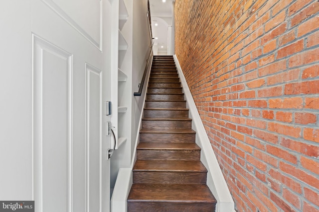 stairway featuring brick wall