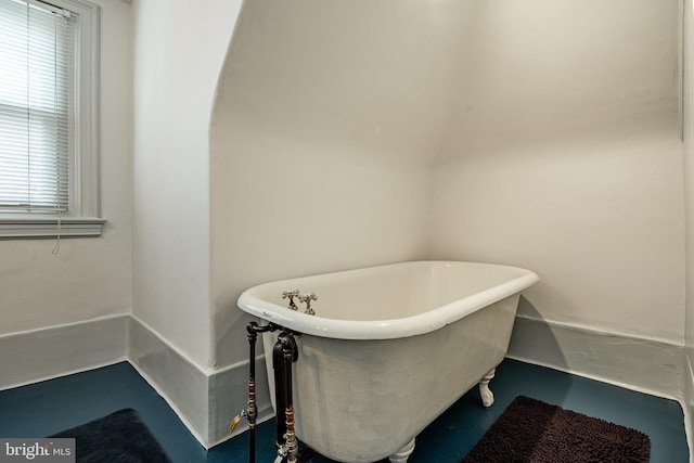 bathroom featuring a tub to relax in and concrete floors