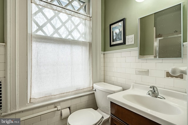 bathroom featuring tile walls, vanity, a shower with door, and toilet