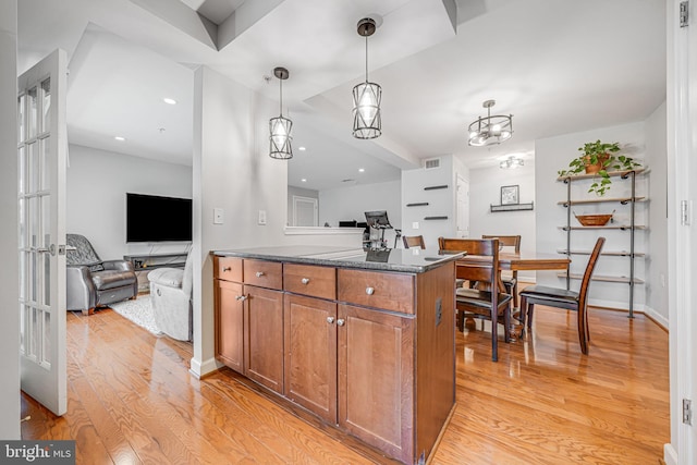 kitchen with light wood-style flooring, brown cabinetry, decorative light fixtures, and open floor plan