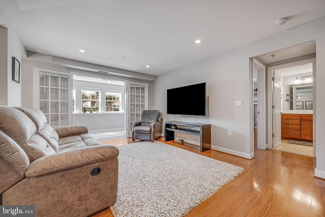 living area with light wood-type flooring, baseboards, and recessed lighting