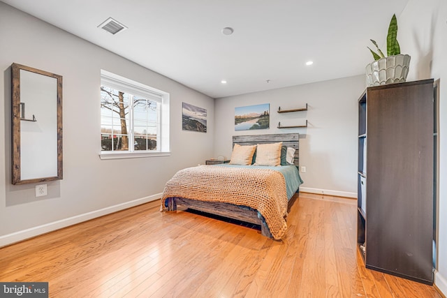 bedroom featuring light wood finished floors, visible vents, and baseboards