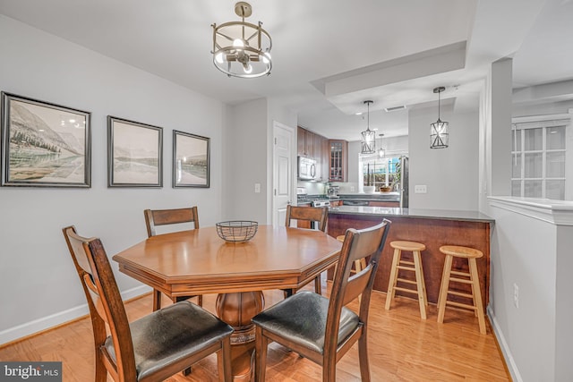 dining room with light wood-type flooring, visible vents, and baseboards