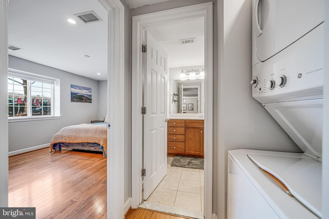 laundry room featuring laundry area, visible vents, light wood finished floors, and stacked washing maching and dryer