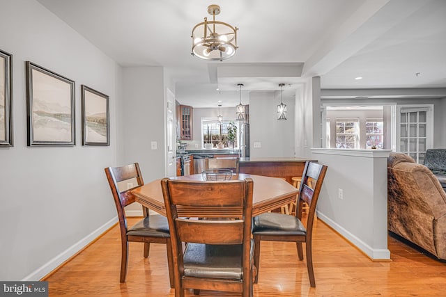 dining room featuring light wood-style floors, baseboards, and a notable chandelier