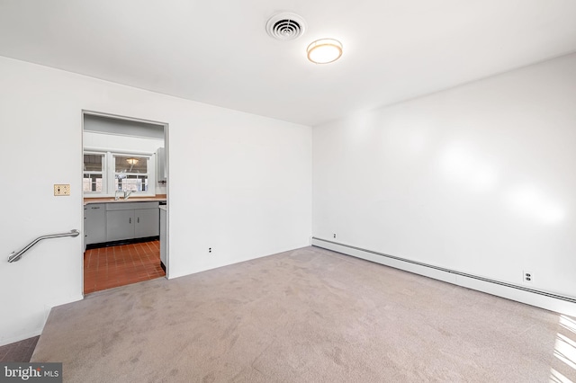 unfurnished room with carpet, a baseboard heating unit, and sink