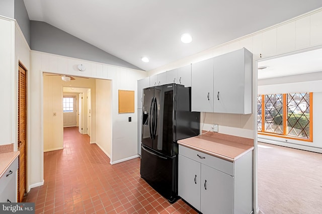 kitchen with lofted ceiling and black fridge with ice dispenser