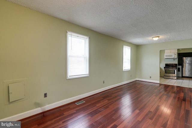 unfurnished living room with light hardwood / wood-style flooring and a textured ceiling