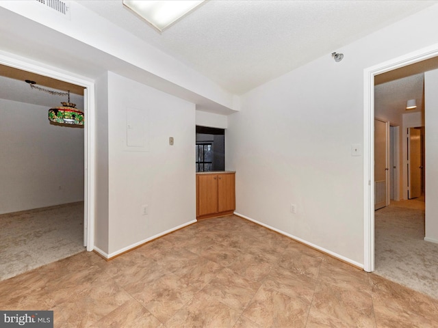 empty room with light colored carpet and a textured ceiling