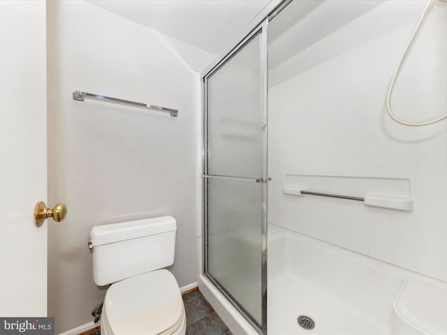 bathroom featuring toilet and a shower with shower door