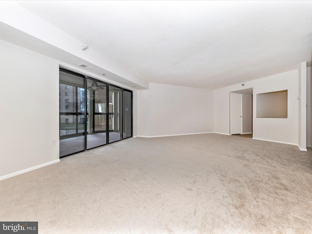 empty room with light colored carpet and a textured ceiling