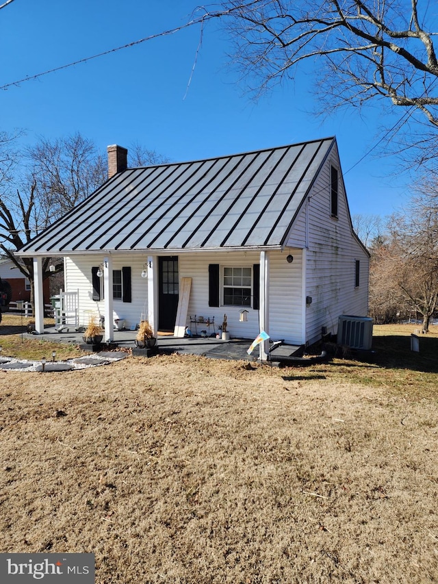 view of front of home featuring covered porch, cooling unit, a front yard, and a patio area