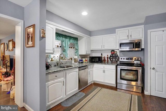 kitchen featuring white cabinetry, appliances with stainless steel finishes, light stone counters, and a sink