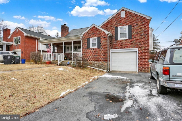 view of front facade featuring driveway, a chimney, an attached garage, a porch, and brick siding