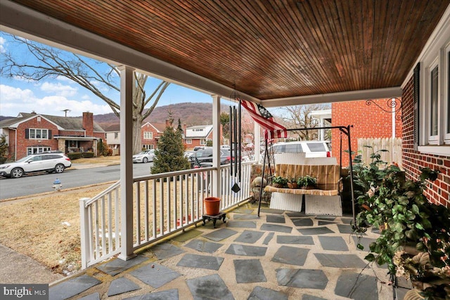 view of patio / terrace with a residential view, covered porch, and a mountain view