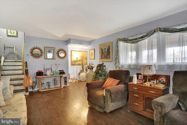 living area featuring stairway, dark wood-style flooring, and a wealth of natural light