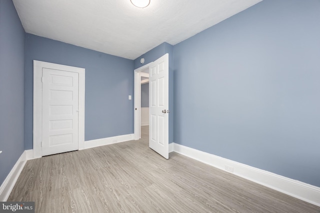 unfurnished bedroom featuring light wood-style flooring and baseboards