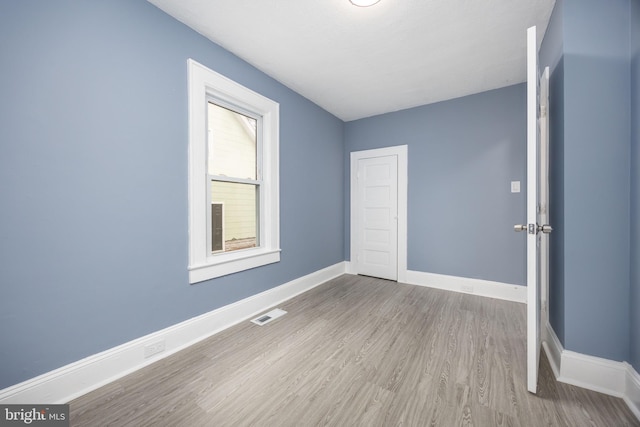 spare room featuring visible vents, baseboards, and wood finished floors