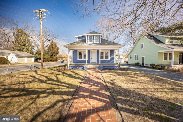 bungalow-style home featuring a porch, roof with shingles, and a front lawn