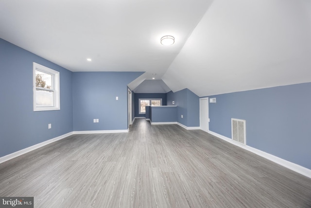 additional living space with plenty of natural light, baseboards, visible vents, and wood finished floors