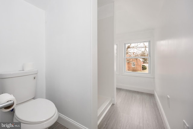 bathroom with wood finished floors, toilet, and baseboards