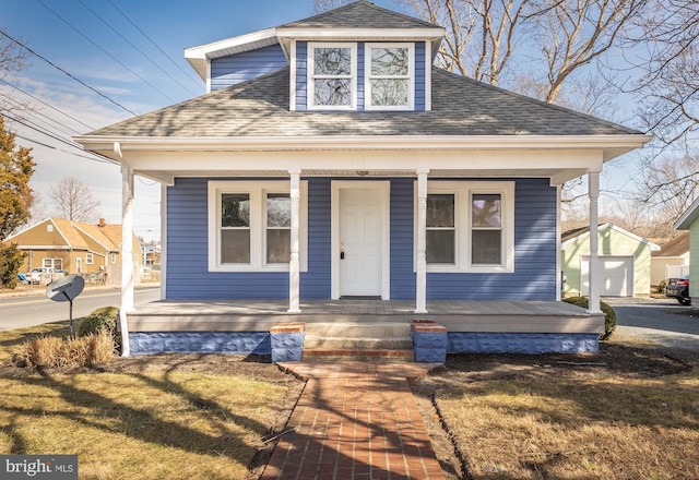 bungalow featuring an outbuilding, a porch, a shingled roof, and a front yard