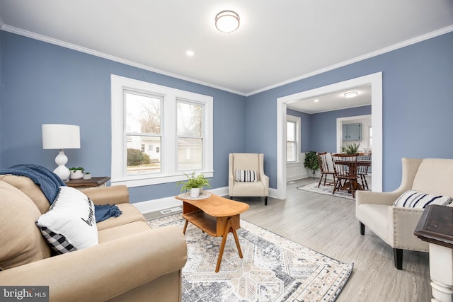 living area featuring ornamental molding, light wood finished floors, and baseboards