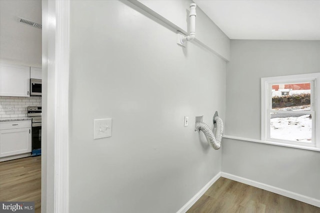 room details featuring white cabinetry, backsplash, light wood-type flooring, and appliances with stainless steel finishes