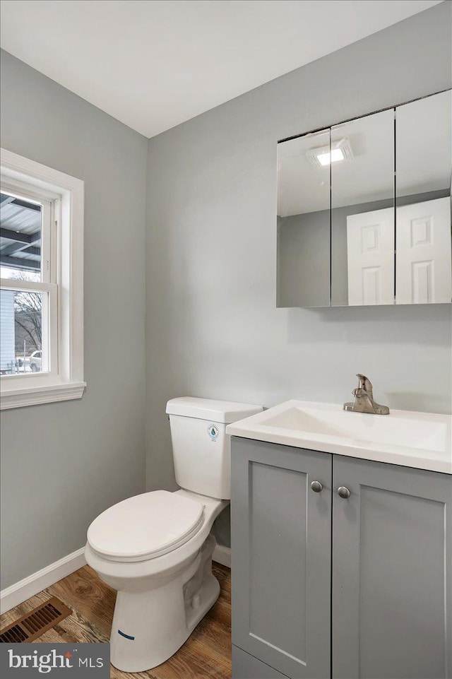 bathroom with wood-type flooring, vanity, and toilet