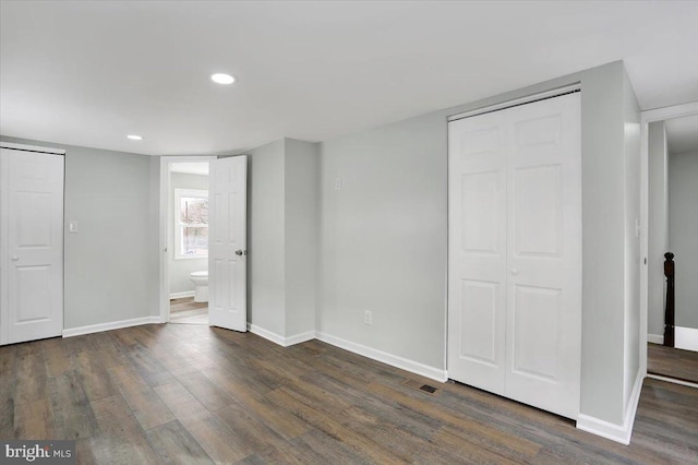 unfurnished bedroom with connected bathroom and dark hardwood / wood-style flooring