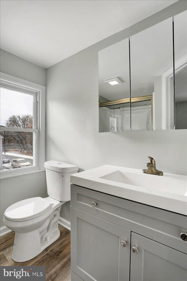 bathroom featuring wood-type flooring, toilet, vanity, and walk in shower