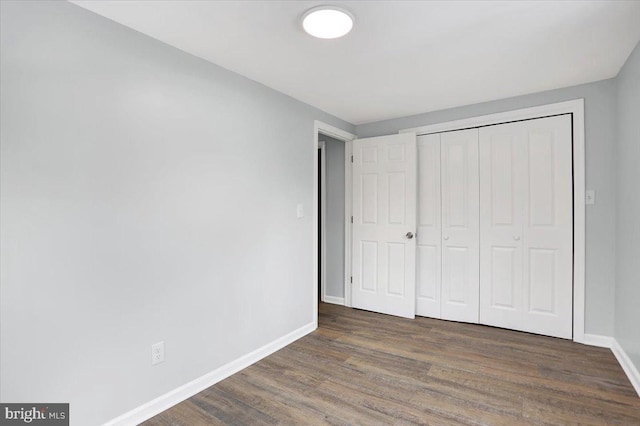 unfurnished bedroom with dark hardwood / wood-style floors and a closet