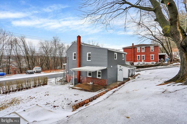 snow covered house featuring central AC