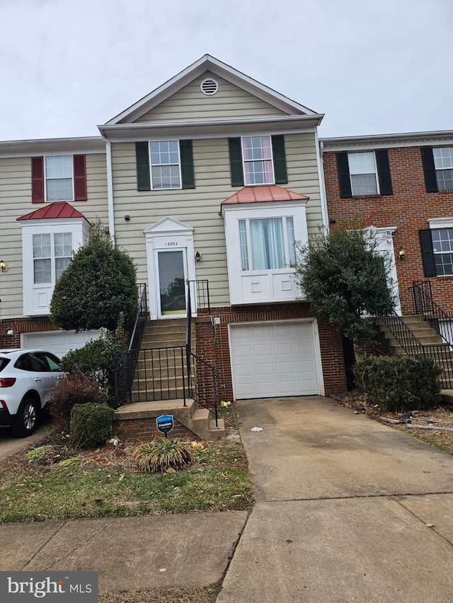 multi unit property with brick siding, an attached garage, and concrete driveway