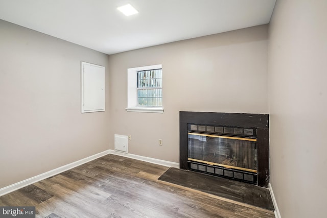 details with a glass covered fireplace, wood finished floors, and baseboards