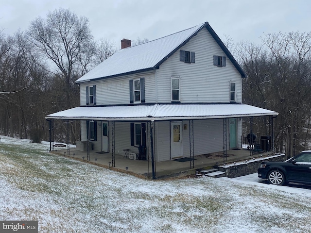 view of front of property featuring metal roof, a porch, and a chimney