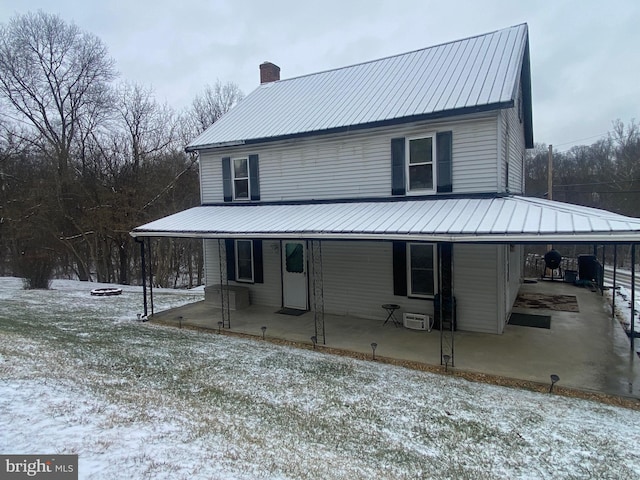 exterior space featuring metal roof, a chimney, and a wall mounted AC