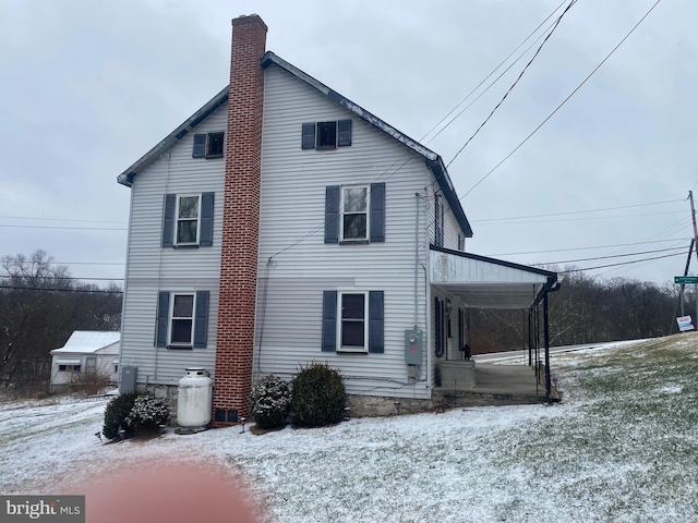 snow covered property with a chimney