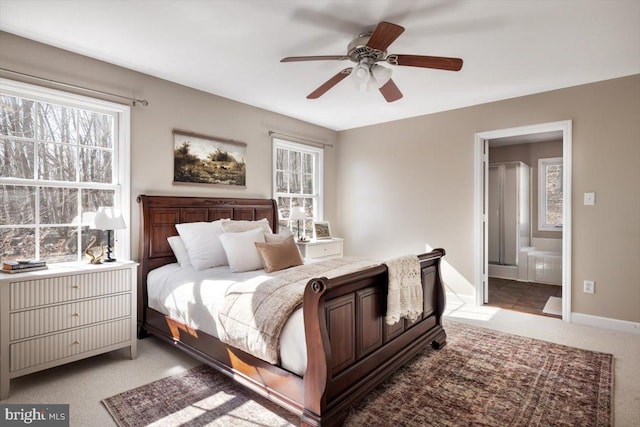 bedroom with multiple windows, light carpet, ceiling fan, and ensuite bathroom