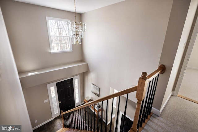 carpeted foyer entrance with a notable chandelier