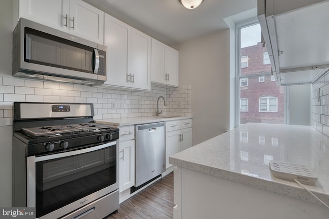 kitchen with stainless steel appliances, white cabinets, a sink, and decorative backsplash