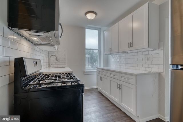 kitchen featuring appliances with stainless steel finishes, white cabinets, a sink, and wood finished floors