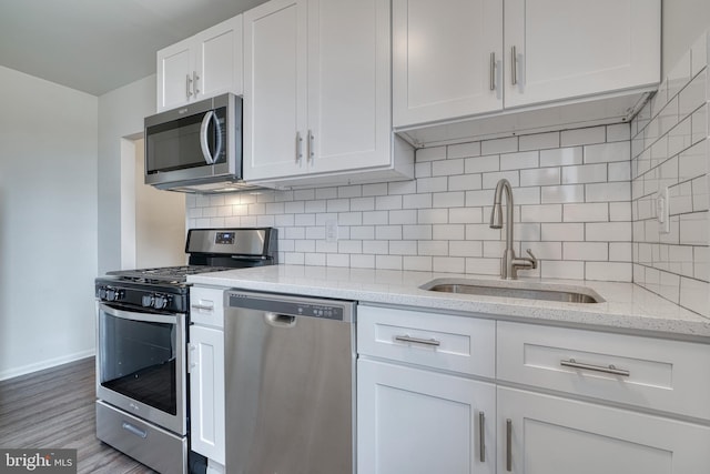 kitchen featuring light stone counters, a sink, white cabinetry, appliances with stainless steel finishes, and backsplash