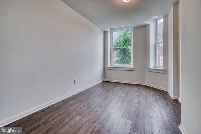 unfurnished room featuring baseboards and dark wood finished floors