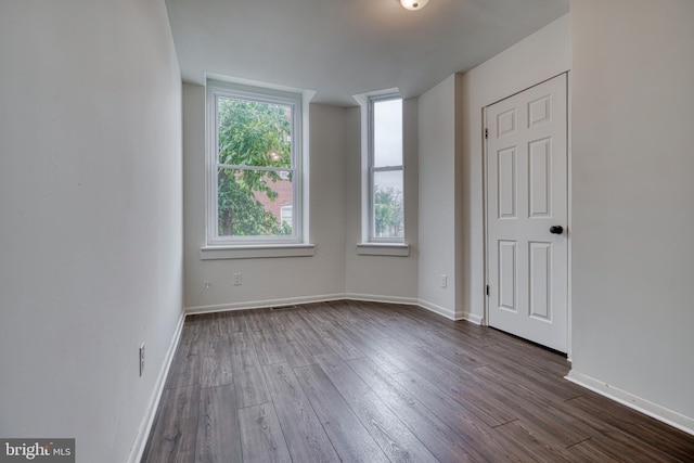 spare room featuring dark wood-style floors and baseboards