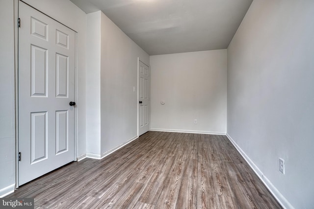 spare room with baseboards and wood finished floors