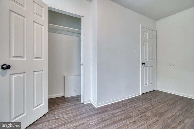 unfurnished bedroom featuring a closet, wood finished floors, and baseboards