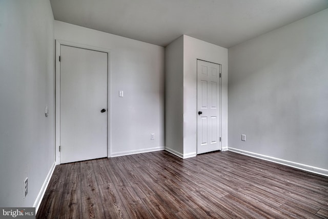 unfurnished bedroom with dark wood-style flooring and baseboards